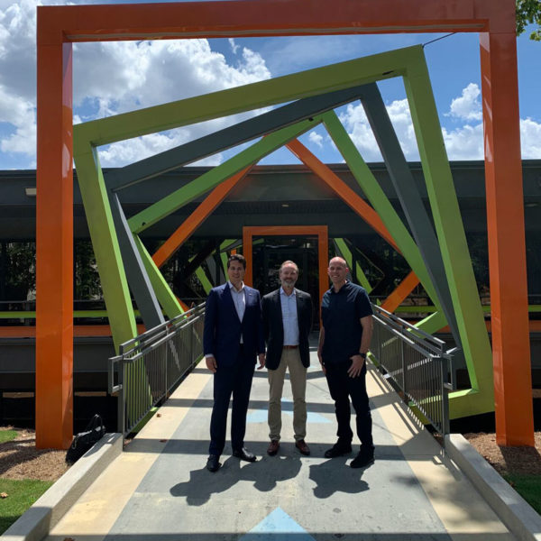 Three people posing in front of the entrance to the Innovation Center