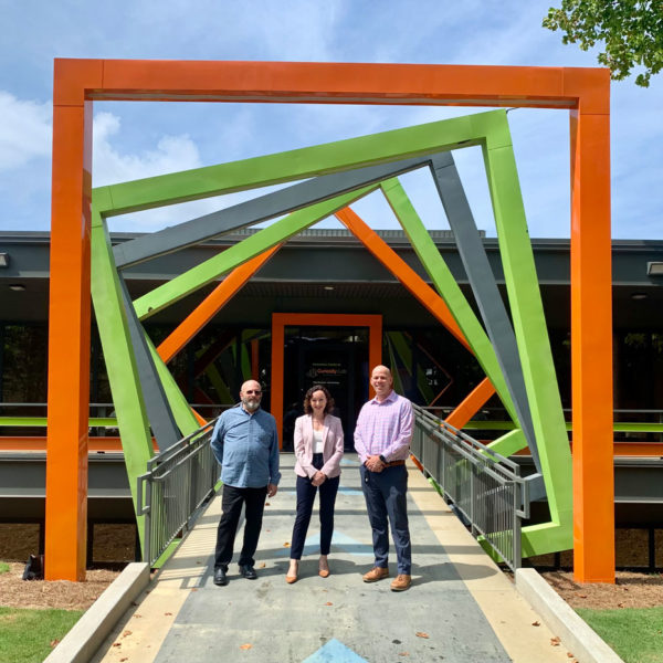 Three people posing in front of the entrance to the Innovation Center